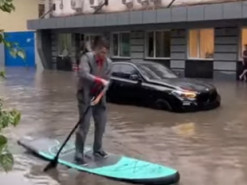 Мужчина в деловом костюме и с веслом "рассекал" по затопленному Киеву на серфе