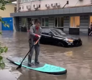 Мужчина в деловом костюме и с веслом "рассекал" по затопленному Киеву на серфе